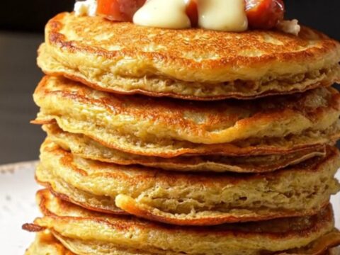 Stack of golden savory pancakes with feta and red peppers on a plate