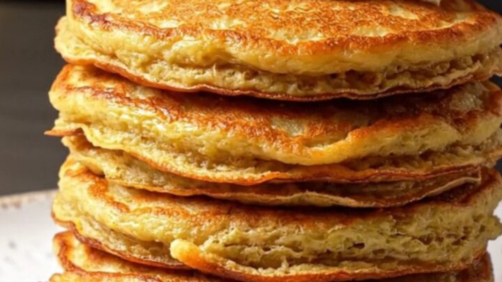 Stack of golden savory pancakes with feta and red peppers on a plate