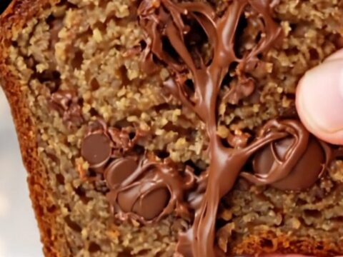 Ultra-moist chocolate chip banana bread loaf with a caramelized top and a banana half baked on top