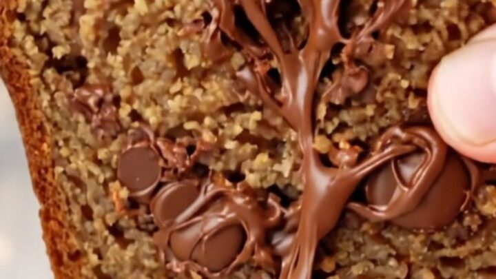 Ultra-moist chocolate chip banana bread loaf with a caramelized top and a banana half baked on top