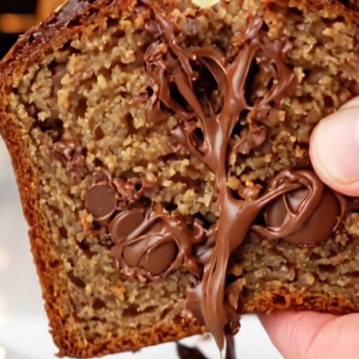 Ultra-moist chocolate chip banana bread loaf with a caramelized top and a banana half baked on top