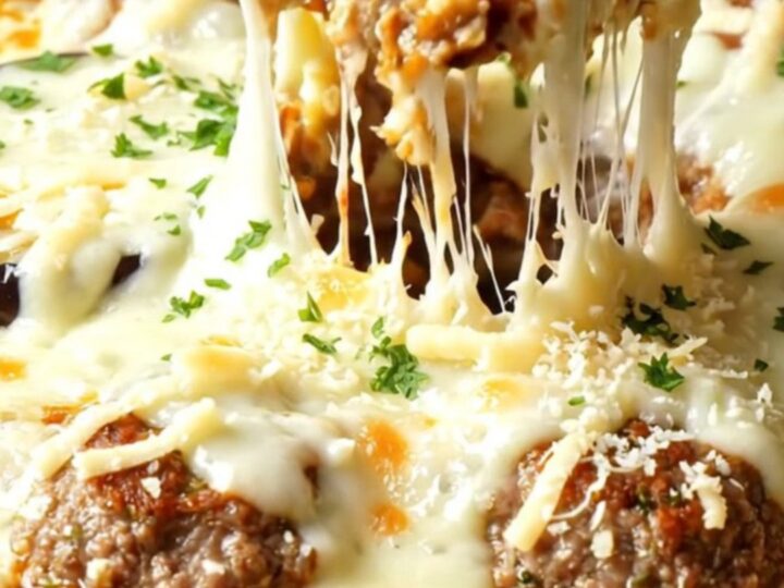 Golden eggplant and meatball skillet with melted cheese pulling in a long strand