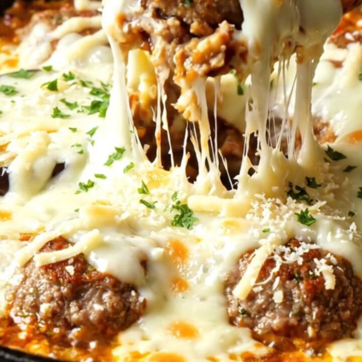 Golden eggplant and meatball skillet with melted cheese pulling in a long strand