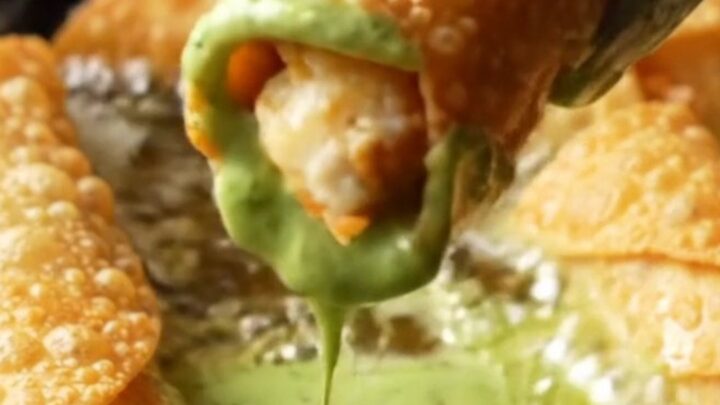 Crispy golden chicken taquitos with a bowl of green crema for dipping