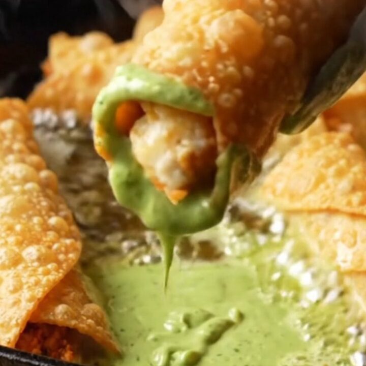 Crispy golden chicken taquitos with a bowl of green crema for dipping