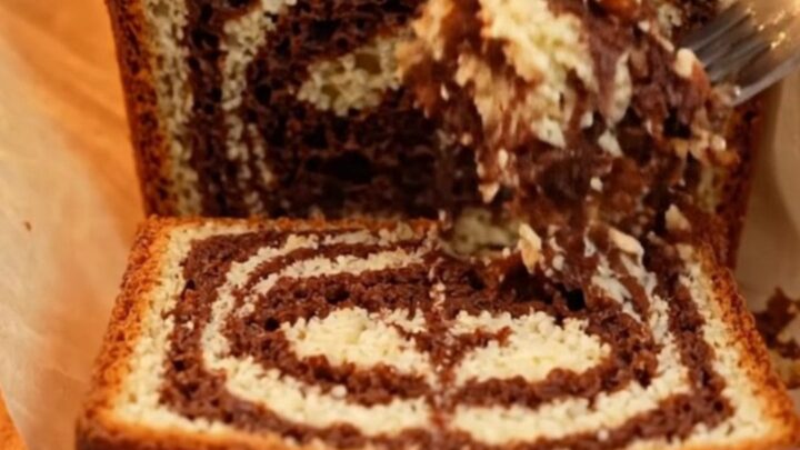 Sliced Turkish marble loaf cake showing dark cocoa swirls and golden crumb, with roasted hazelnuts on top