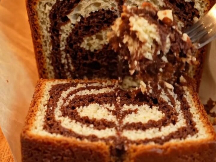 Sliced Turkish marble loaf cake showing dark cocoa swirls and golden crumb, with roasted hazelnuts on top