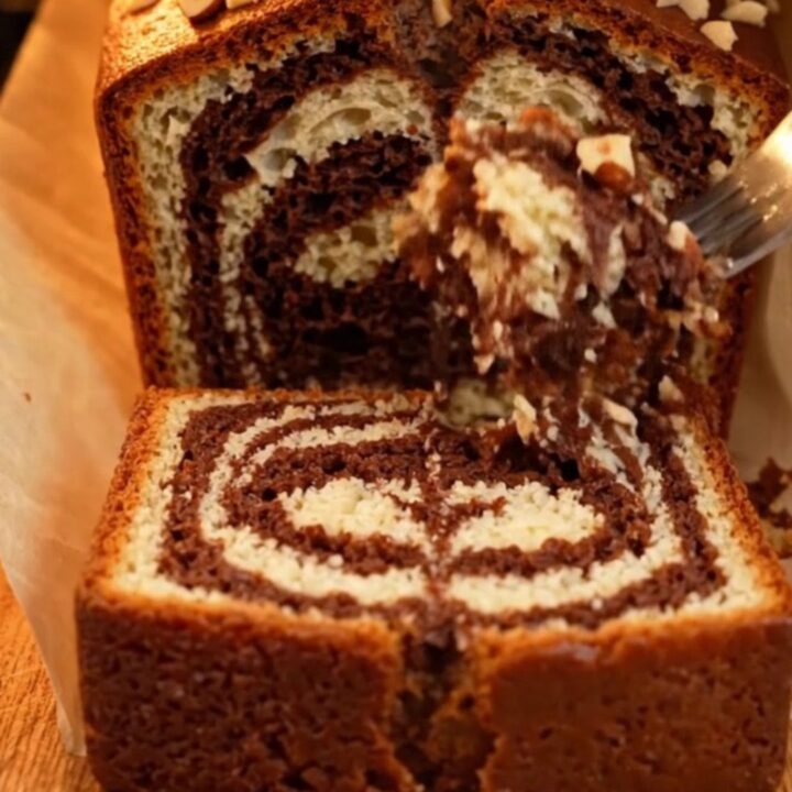 Sliced Turkish marble loaf cake showing dark cocoa swirls and golden crumb, with roasted hazelnuts on top