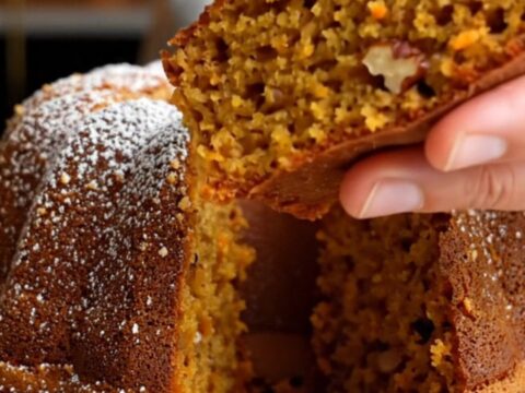 Spiced Turkish carrot walnut bundt cake on a wooden board, dusted with confectioners' sugar