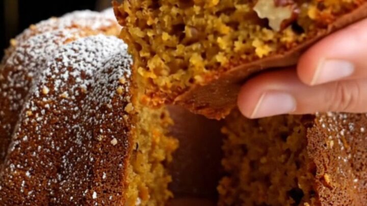 Spiced Turkish carrot walnut bundt cake on a wooden board, dusted with confectioners' sugar