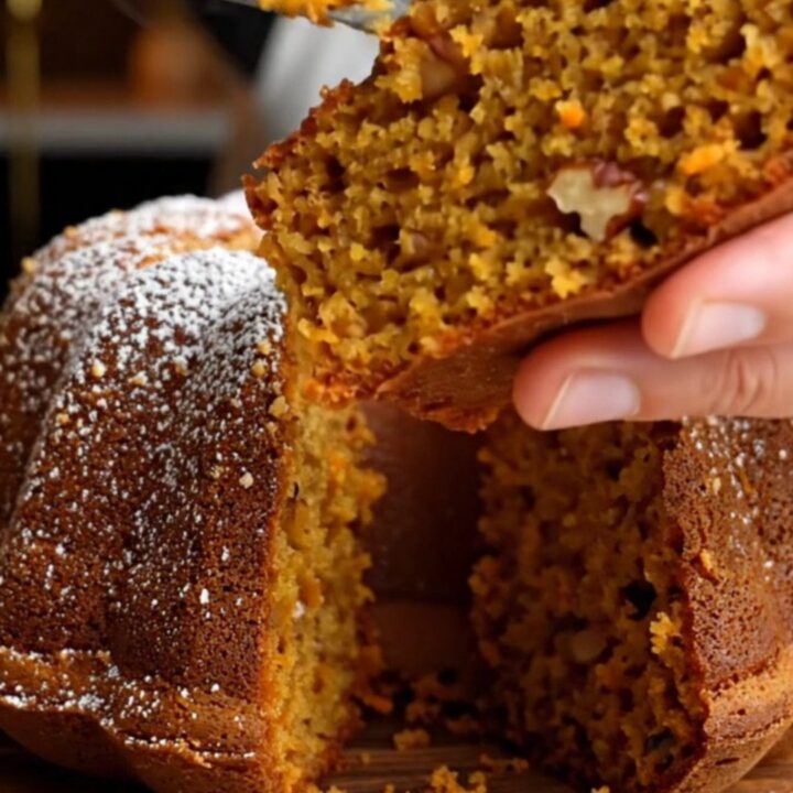 Spiced Turkish carrot walnut bundt cake on a wooden board, dusted with confectioners' sugar