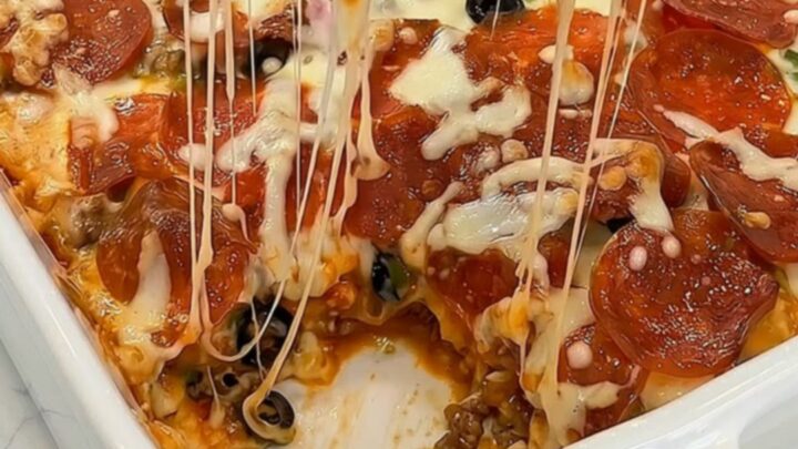 A golden, bubbling loaded bubble up pizza bake served in a white baking dish with melted mozzarella cheese pulls.