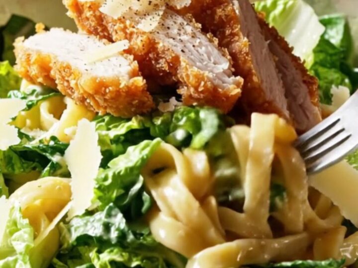 Crispy chicken strips on top of creamy Caesar pasta salad with shaved Parmesan