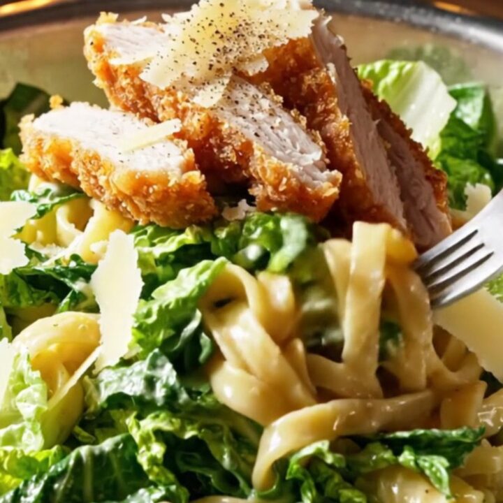Crispy chicken strips on top of creamy Caesar pasta salad with shaved Parmesan