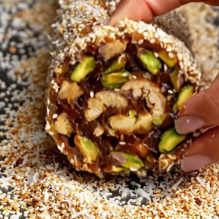 No-Bake Medjool Date and Nut Energy Roll sliced into thick medallions showing pistachios and walnuts.
