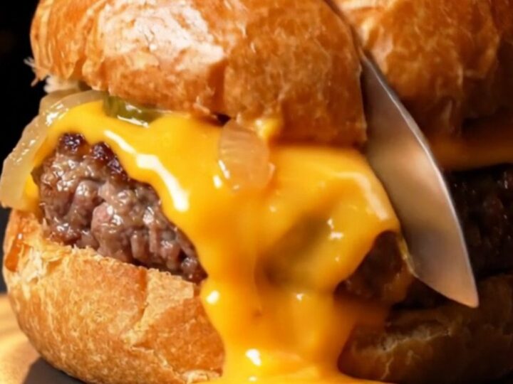 Golden brioche pockets with sesame seeds, one sliced open showing molten cheddar and juicy beef