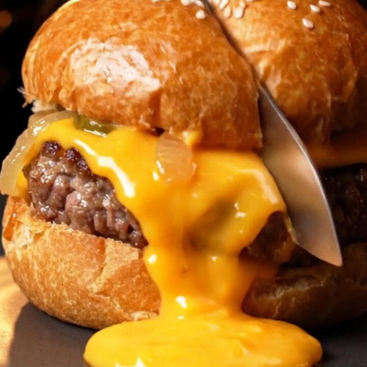 Golden brioche pockets with sesame seeds, one sliced open showing molten cheddar and juicy beef