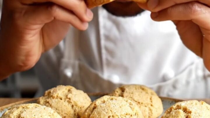 Golden tahini walnut cookies with cracked tops on a parchment-lined baking sheet