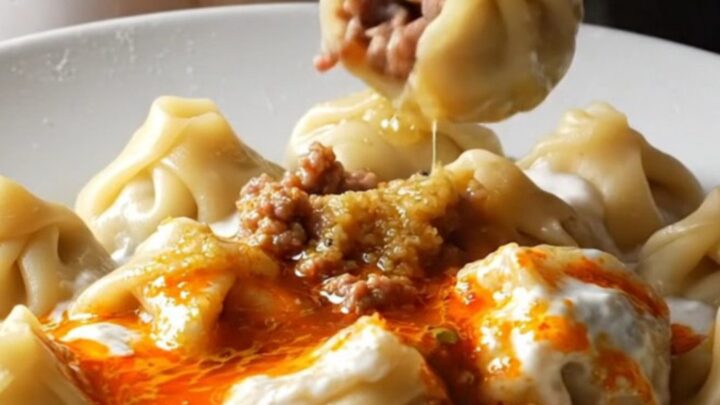 Honeycomb Turkish mantı dumplings in a shallow bowl, topped with garlic yogurt and sizzling red paprika mint butter.