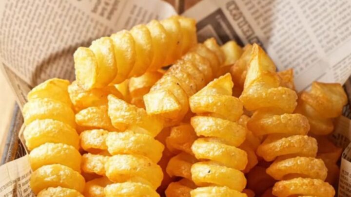 Golden spiral potato fries piled high on a paper-lined basket, with a crispy texture visible.