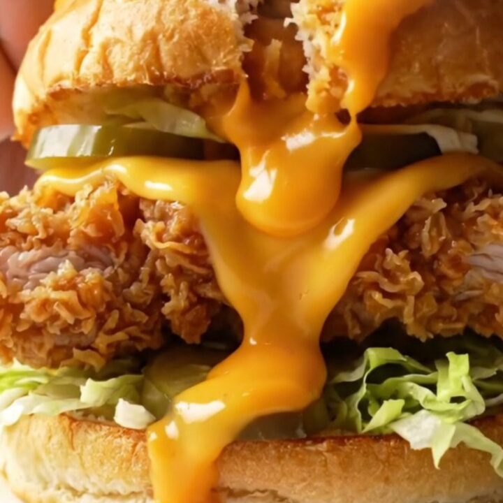Crispy fried chicken sandwich with melted cheese, pickles, and lettuce on toasted bread