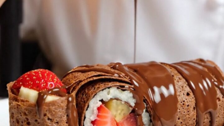 Chocolate crepe dessert sushi rolls sliced and arranged on a plate, showing strawberry and banana centers
