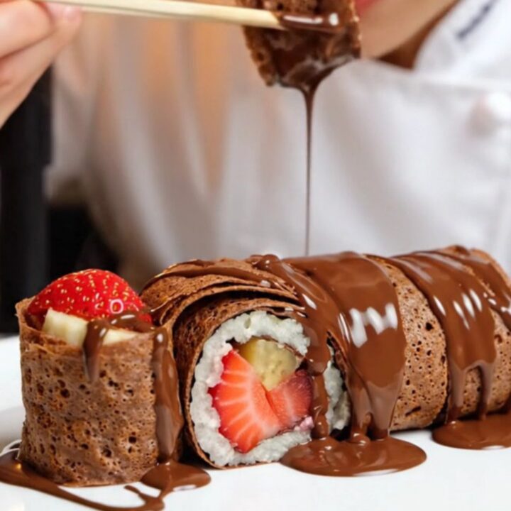 Chocolate crepe dessert sushi rolls sliced and arranged on a plate, showing strawberry and banana centers