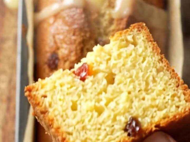 Golden boiled lemon loaf cake drizzled with tart glaze, showing tender yellow crumb and dried fruit jewels