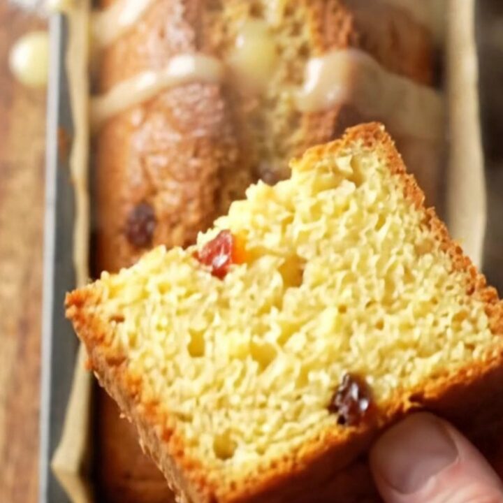 Golden boiled lemon loaf cake drizzled with tart glaze, showing tender yellow crumb and dried fruit jewels