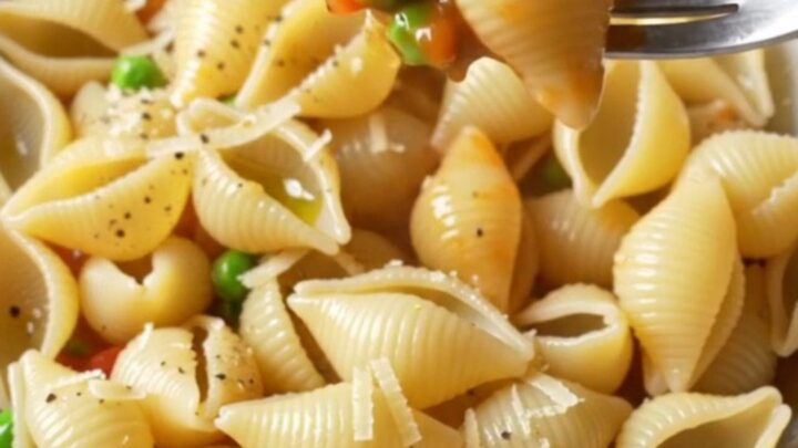 A bowl of shell pasta with beef ragù, topped with grated pecorino and a drizzle of olive oil.
