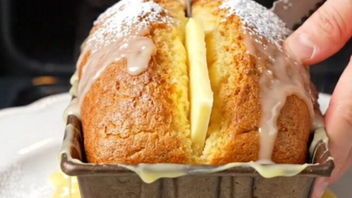 Whole lemon cake with glossy white glaze, sliced to show moist crumb