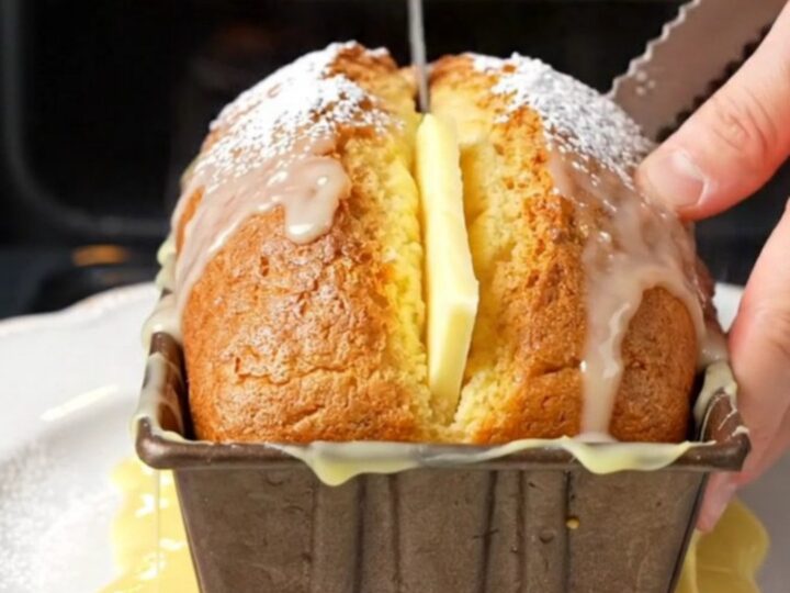 Whole lemon cake with glossy white glaze, sliced to show moist crumb