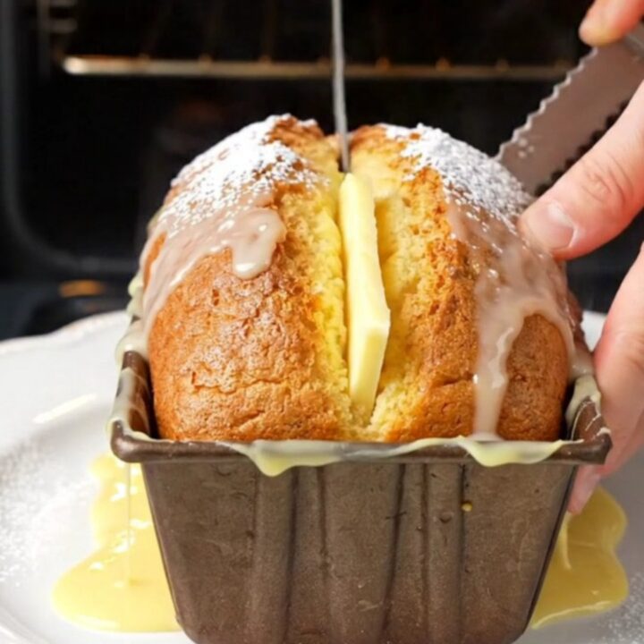 Whole lemon cake with glossy white glaze, sliced to show moist crumb