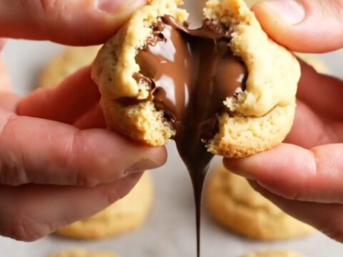 Golden shortbread cookie broken in half with molten chocolate oozing out