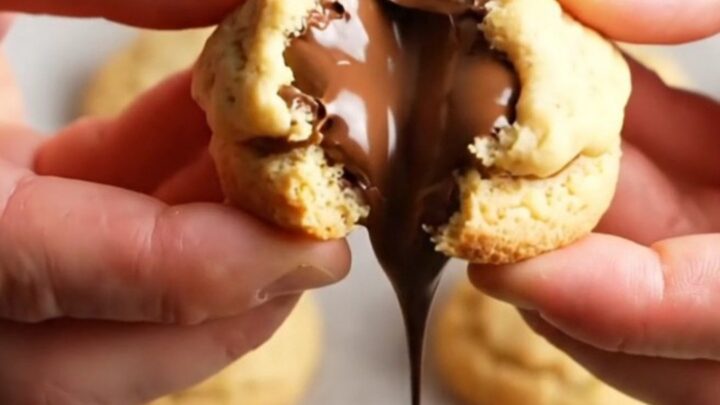 Golden shortbread cookie broken in half with molten chocolate oozing out
