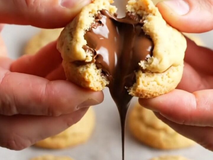 Golden shortbread cookie broken in half with molten chocolate oozing out
