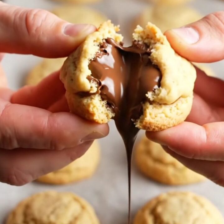 Golden shortbread cookie broken in half with molten chocolate oozing out