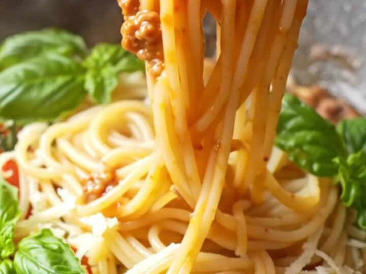 Twirled spaghetti coated in rich tomato meat sauce with melted mozzarella and fresh basil