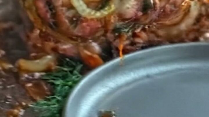 A sliced pork roulade showing a beautiful herb-filled spiral and crispy bacon crust.