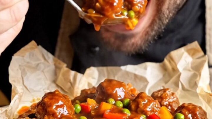 A baking dish filled with tender meatballs, golden eggplant and potatoes, peas, and peppers in a rich tomato sauce.
