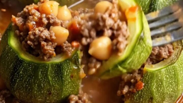 Braised stuffed round zucchini on a plate with tomato broth spooned over