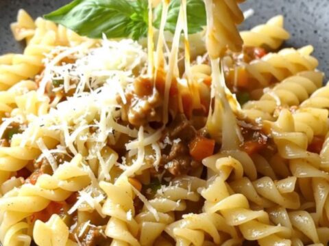 One-pan fusilli with vegetable meat ragù in a skillet, topped with melted mozzarella and parsley.