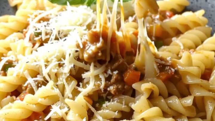 One-pan fusilli with vegetable meat ragù in a skillet, topped with melted mozzarella and parsley.