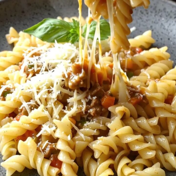 One-pan fusilli with vegetable meat ragù in a skillet, topped with melted mozzarella and parsley.