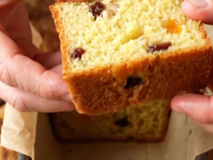 Golden whole lemon loaf with dried fruits, sliced to show moist crumb