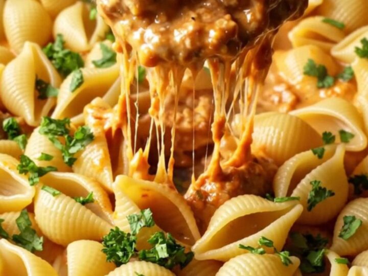 A skillet filled with creamy tomato pasta and mini meatballs, garnished with parsley.