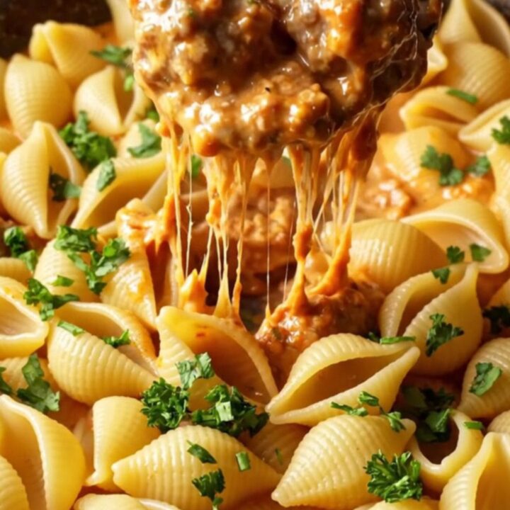A skillet filled with creamy tomato pasta and mini meatballs, garnished with parsley.