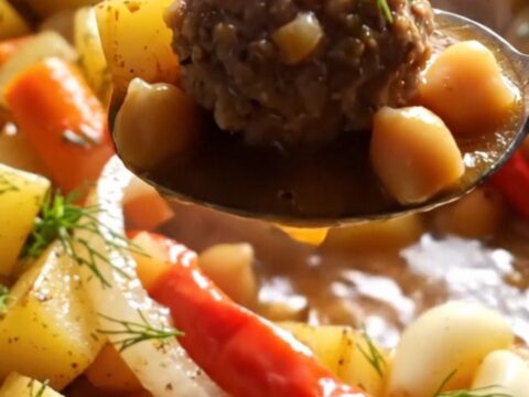 A bowl of Turkish meatball stew with meatballs, potatoes, chickpeas, and tomato broth