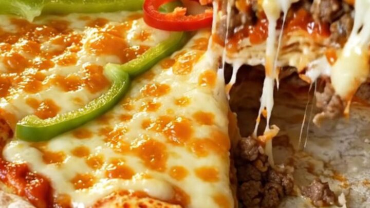 A tall layered lavaş pizza pie with golden melted cheese, cherry tomatoes, and green pepper on top