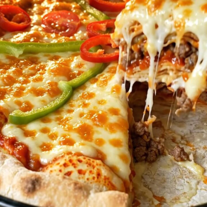 A tall layered lavaş pizza pie with golden melted cheese, cherry tomatoes, and green pepper on top